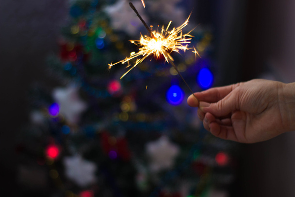 Soft and blur conception.Female hand holding a burning sparklers closeup. New Year's and Christmas - Foto, imagen