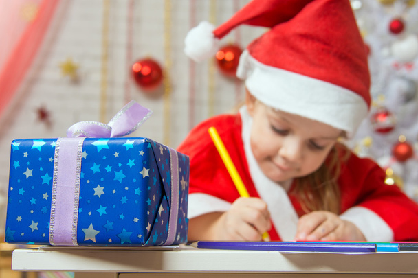 Новорічний подарунок на передньому плані, на задньому плані Дівчина малює олівець
 - Фото, зображення