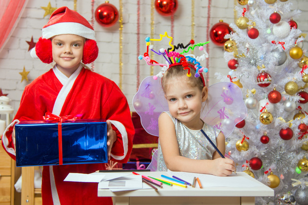 Fille assise à une table avec des feux d'artifice sur la tête, Père Noël est un peu derrière avec un cadeau
 - Photo, image