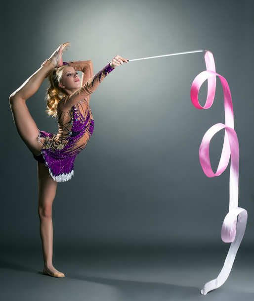 Cute gymnast dancing with ribbon, on gray backdrop - Foto, Bild