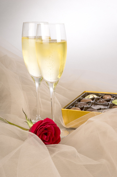 シャンパン、単一の赤いバラ、グルメ チョコレートのオープン ボックスの 2 つのメガネ - 写真・画像
