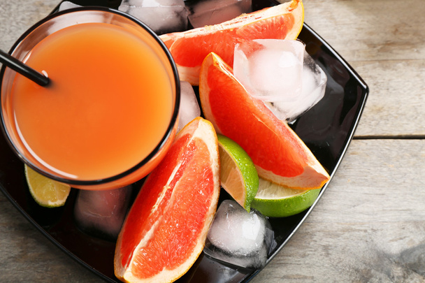 Citrus juice and fresh fruits on black plate - Foto, Bild
