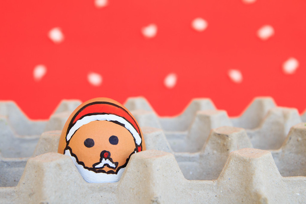 Vánoční vejce s tváře byly uspořádány v kartonu na sněhu pozadí - Fotografie, Obrázek