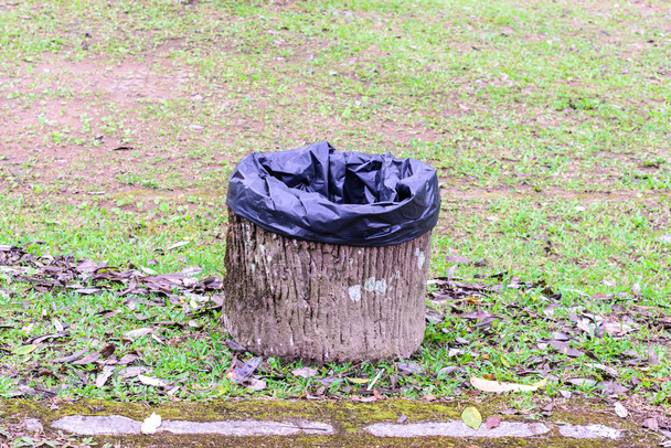Poubelle en ciment avec sac noir au jardin urbain
. - Photo, image