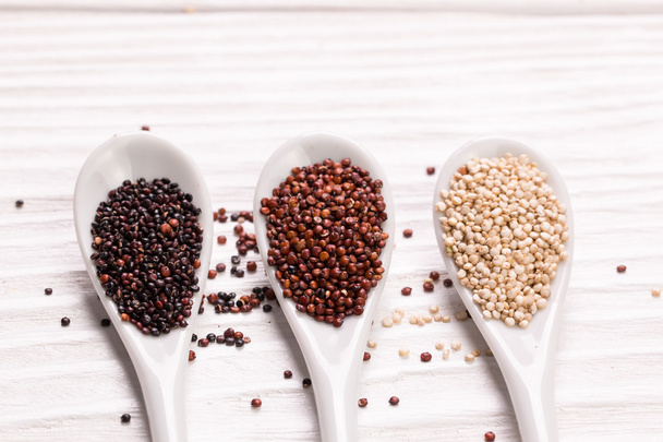 Red, black and white quinoa seeds on a wooden background - Valokuva, kuva