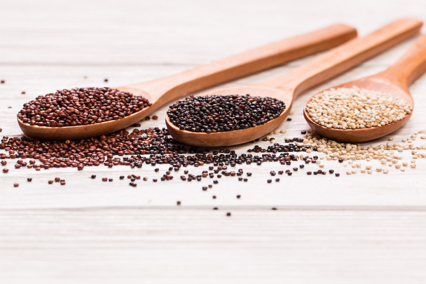 Red, black and white quinoa seeds on a wooden background - Foto, imagen