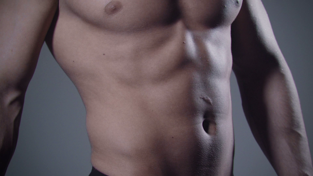 Primer plano del cuerpo masculino muscular sobre fondo gris
. - Metraje, vídeo