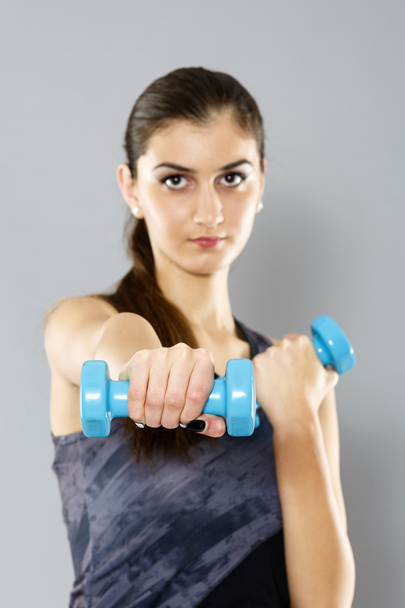 sporty woman do her workout with dumbbells, isolated on gray bac - Foto, afbeelding