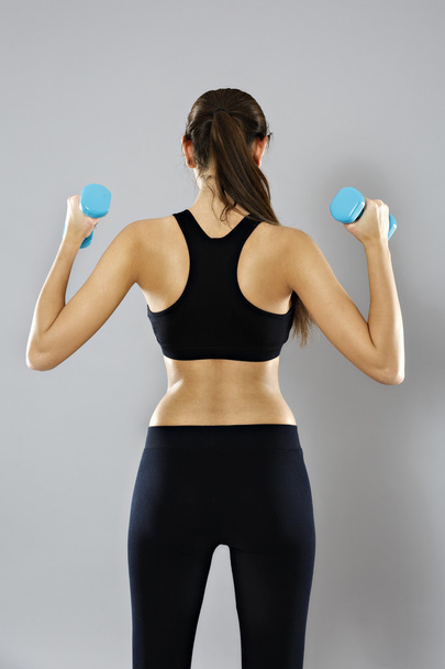 sporty woman do her workout with dumbbells, isolated on gray bac - Foto, immagini