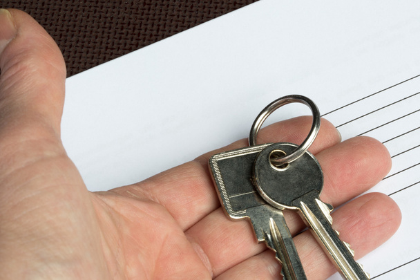 Пара ключей в руке с чистой бумагой
 - Фото, изображение
