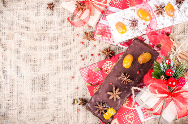 Chocolate spices cake, star anise and dried fruits, packed gifts with red tapes on sackcloth, canvas. Sweet frame. Free space for your text. - Photo, Image