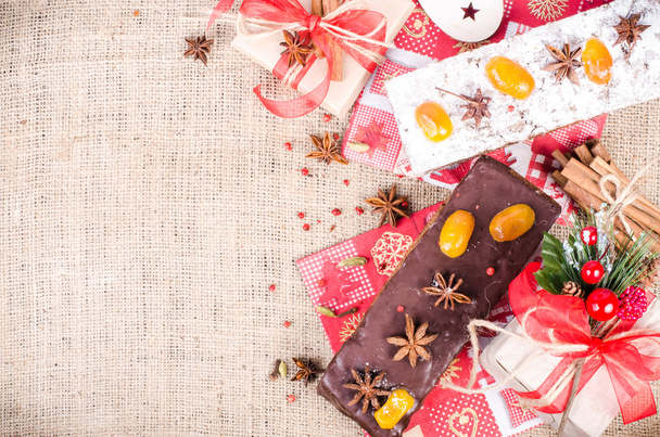 Chocolate spices cake, star anise and dried fruits, packed gifts with red tapes on sackcloth, canvas. Sweet frame. Free space for your text. - 写真・画像