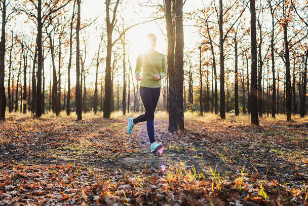 female running in park. Young woman jogging in autumn forest - Foto, Imagem