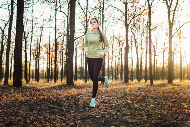 female running in park. Young woman jogging in autumn forest - Фото, зображення