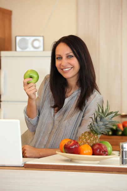 Woman with an apple in the kitchen - Foto, imagen