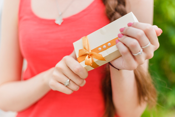 niña mantener pequeño regalo con cinta cerca de las manos sosteniendo
 - Foto, imagen