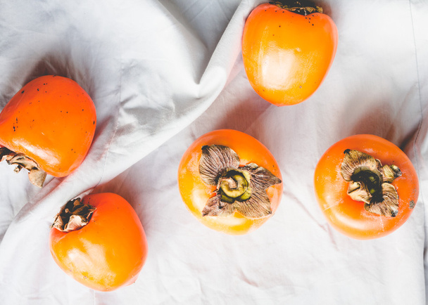 Fresh juicy persimmons on a light background, raw fruit - 写真・画像