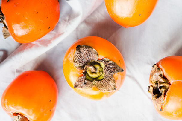 Fresh juicy persimmons on a light background, raw fruit - Фото, изображение