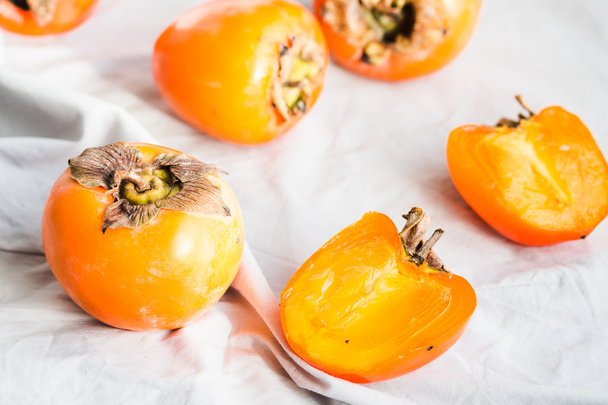 Fresh juicy persimmons on a light background, raw fruit - Photo, image