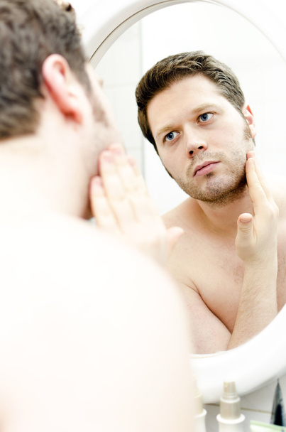 El hombre mira su barba y piensa en afeitarse
 - Foto, Imagen
