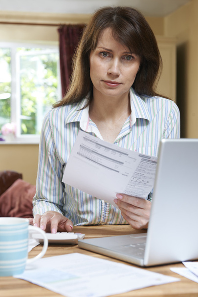 Беспокойная женщина средних лет смотрит на домашние финансы
 - Фото, изображение