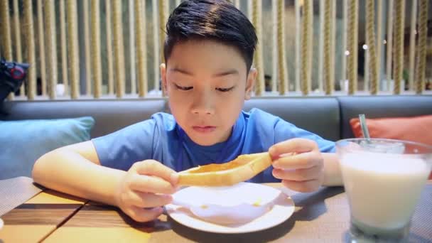 Ευτυχισμένος Ασίας αγόρι που τρώνε φέτα ψωμί με πρόσωπο χαμόγελο - Πλάνα, βίντεο