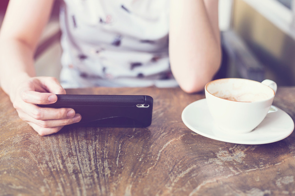 ręka kobiety za pomocą smartphone w kawiarni i miękkie światło - Zdjęcie, obraz