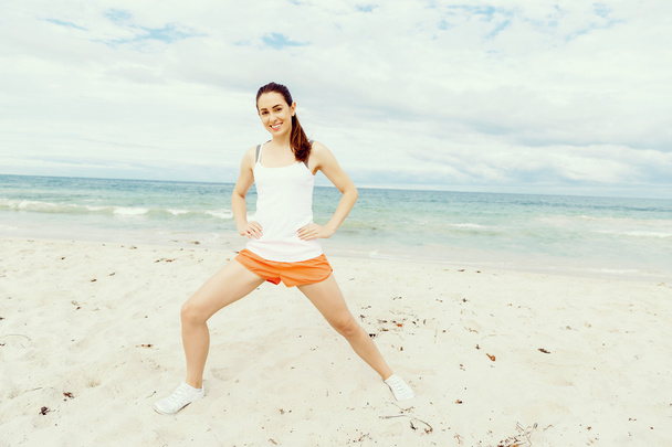 Young woman training on beach outside - Фото, изображение