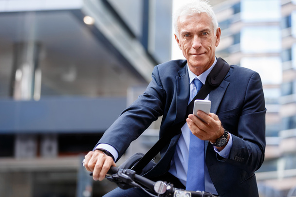 Successful businessman on bicycle with mobile phone - Foto, afbeelding