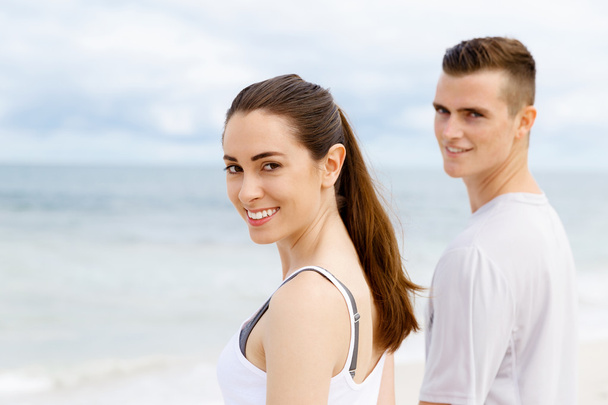 Νεαρό ζευγάρι ψάχνει στοχαστικό ενώ στέκεται δίπλα στην άλλη στην παραλία - Φωτογραφία, εικόνα