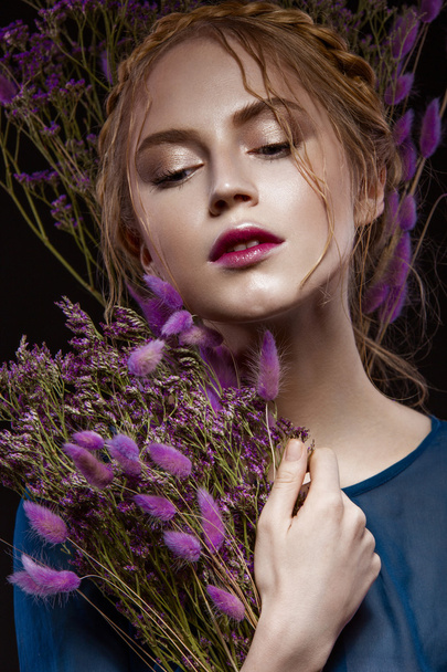 Beautiful girl with a gentle make-up, hairstyle  in the form of braids,  dry flowers, blue dress. Beauty face. - Photo, image