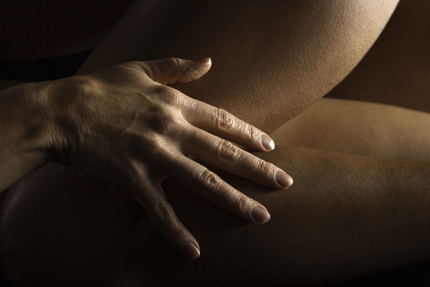 Female hand on thigh. - Foto, afbeelding
