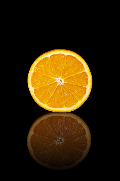 Half orange on a black reflective background - Foto, afbeelding
