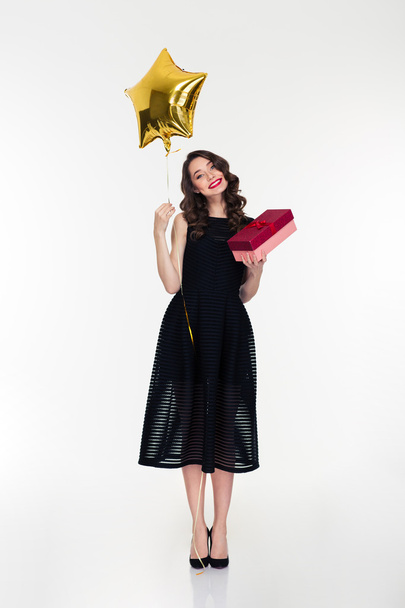 Smiling woman holding golden star shaped balloon and present box - Foto, Imagem