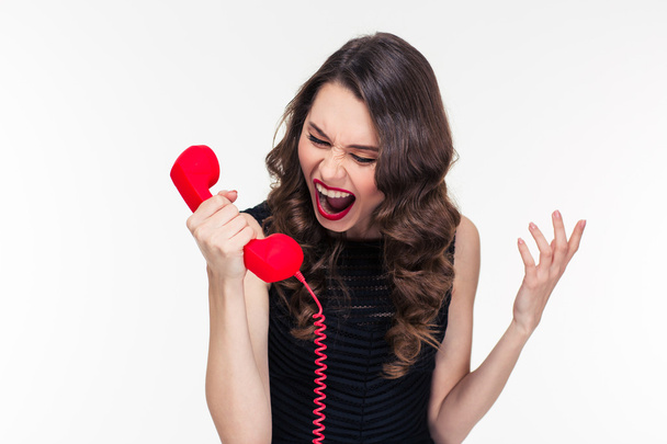 Crazy raged retro styled female shouting in red telephone receiver  - Foto, imagen
