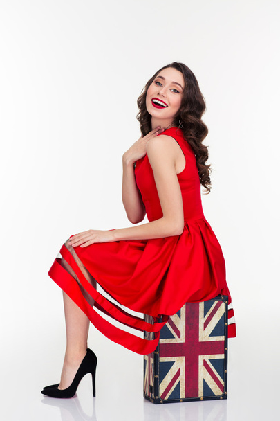 Charming happy woman posing on vintage suitcase with british flag - Foto, immagini