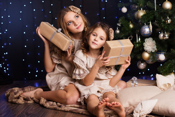 Two girls are sitting near christmas tree - Foto, afbeelding