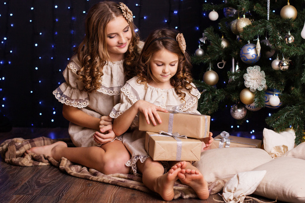 Two girls are sitting near christmas tree at home - Photo, image