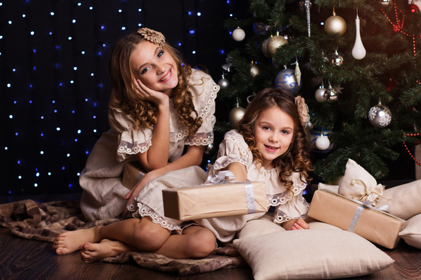 Two sisters with christmas gifts at home - Fotoğraf, Görsel
