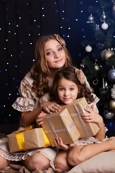 Two girls friends with gifts near christmas tree - Fotoğraf, Görsel