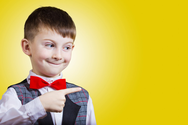 Surprised Pointing little boy isolated over yellow background. - 写真・画像