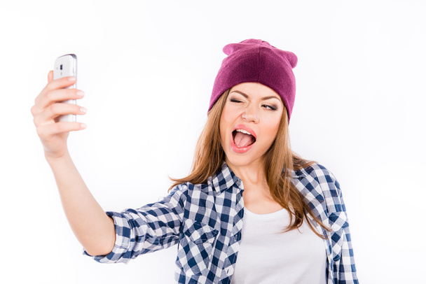 funny girl in a hipster hat making selfe photo on the phone  - Zdjęcie, obraz
