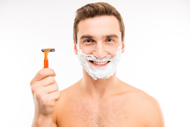 Handsome happy man with shaving foam on his face holding razor - Foto, Imagen