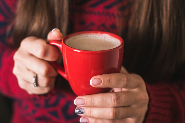 Дівчина в червоному светрі тримає червону чашку кави
 - Фото, зображення