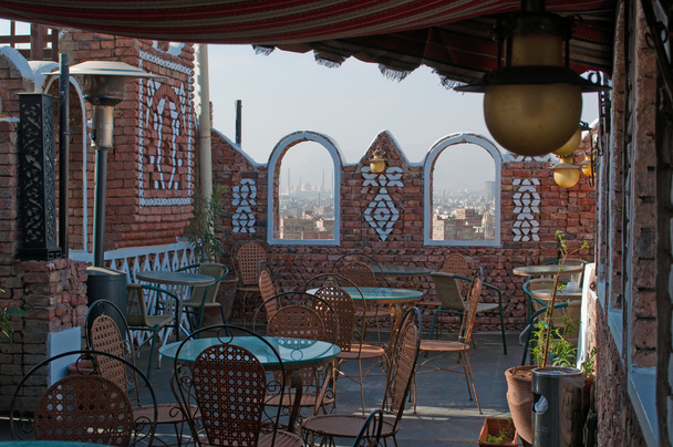 Yemen, Middle East: tables on a roof terrace with view of the Old City of Sana'a with the Saleh Mosque in the fog behind the stone arches - Photo, Image