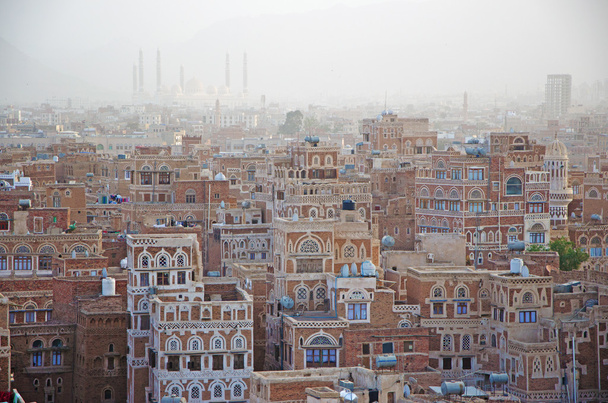 Jemen, Midden-Oosten: luchtfoto van de skyline van de hoofdstad Sanaa, Unesco wereld erfgoed site, met de Al Saleh Mosque in de mist en de unieke paleizen en huizen van de stenen toren versierd met geometrische patronen van gebakken bakstenen en witte gips - Foto, afbeelding