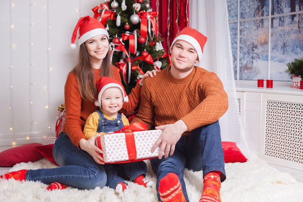 Happy family at Christmas eve sitting together near decorated tree - Фото, зображення