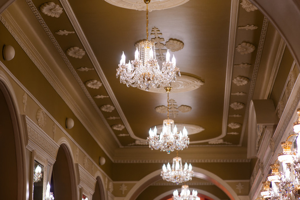 Beautiful glowing chandeliers in the hall of the palace - Photo, Image