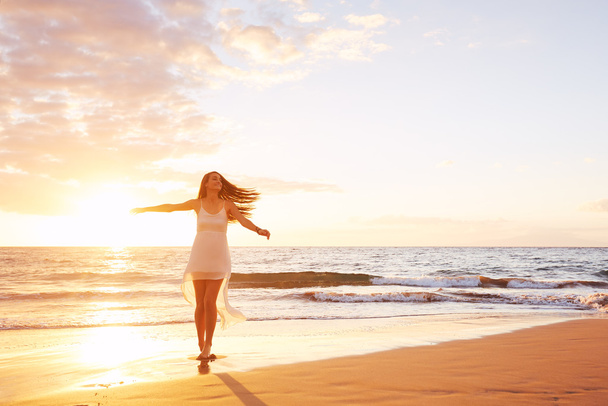 Heureuse femme insouciante dansant sur la plage au coucher du soleil
 - Photo, image