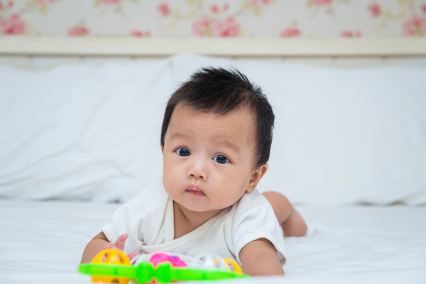 Portret van schattige babymeisje op het bed met speelgoed - Foto, afbeelding